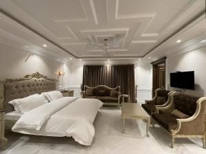 a bedroom with a bed and two chairs and a television at Arish Luxury Suites in Skardu