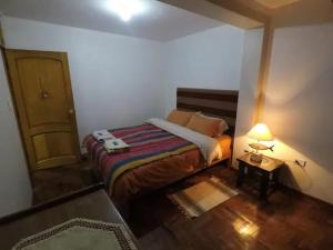 a bedroom with a bed with a lamp and a door at Apart Happy Cata in Puno