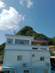 a large white building with a hill in the background at 蘭嶼小島觀海旅宿 in Lanyu