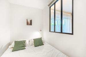 a white bedroom with a bed with a window at Lavie Maison Balneo garden flat in Bordeaux