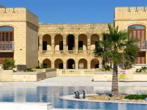 a building with a palm tree in front of it at Fort Chambray Apartment in Għajnsielem
