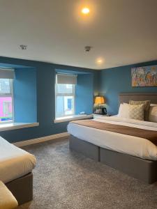 1 dormitorio con 2 camas, paredes y ventanas azules en The Townhouse, en Miltown Malbay