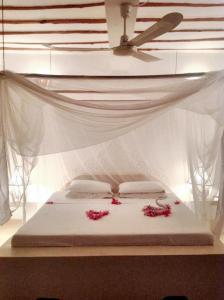uma cama com flores cor-de-rosa com tecto em 3 bedrooms house at Watamu 100 m away from the beach with shared pool furnished terrace and wifi em Watamu