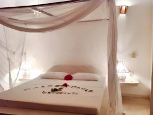 um quarto com uma cama de dossel branca em 3 bedrooms house at Watamu 100 m away from the beach with shared pool furnished terrace and wifi em Watamu