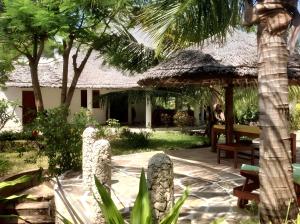 a patio with a thatch umbrella and a bench at 3 bedrooms house at Watamu 100 m away from the beach with shared pool furnished terrace and wifi in Watamu