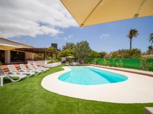 uma piscina num quintal com cadeiras e um guarda-sol em CASA GRAN CANARIA - Gran Canaria Stays em Maspalomas