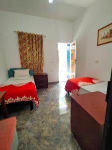 - une chambre avec 2 lits avec des draps rouges et une fenêtre dans l'établissement Blue Bus Camp Resort, à Nuweiba