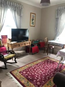 a living room with a flat screen tv and a rug at Sunny Bank Guest House in Hythe