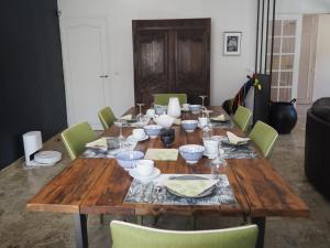 une table en bois entourée de chaises vertes dans l'établissement chambre chez l'habitant JO 2024, à Villiers-sur-Orge