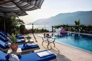 a swimming pool with blue chairs and an umbrella at Bella Vista, Kaş Antalya in Kaş