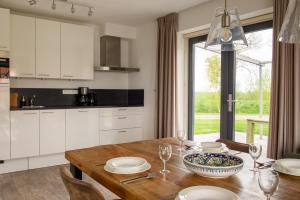 a kitchen with white cabinets and a wooden table at Dormio Waterpark Langelille in Langelille