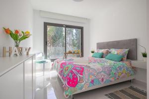 sypialnia z łóżkiem z kolorową kołdrą i oknem w obiekcie Apartment Marbella Golf With Pool - Happy Rentals w mieście Estepona