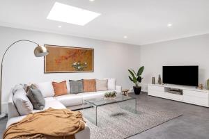 a white living room with a couch and a tv at Beautiful Balmain Abode - Balmain, NSW in Sydney