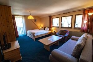 a hotel room with a couch and a bed and a tv at Gasthof Braun in Schmallenberg