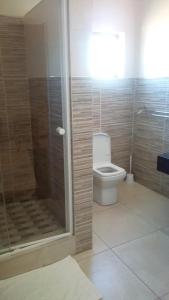 a bathroom with a toilet and a glass shower at LOTUS LODGE in Gaborone