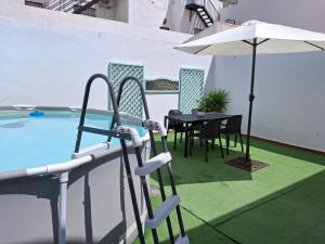 patio con tavolo e ombrellone accanto alla piscina di Casa Yerbabuena a La Puebla de Cazalla