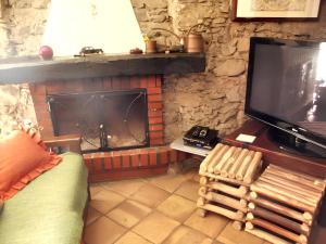 ein Wohnzimmer mit einem Kamin und einem TV in der Unterkunft 2 bedrooms house with sea view furnished terrace and wifi at Castelmola 5 km away from the beach in Castelmola
