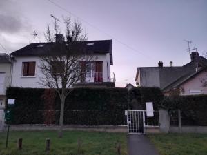 a white house with a fence and a tree at Appartement meublé à 30 minutes de Paris in Mantes-la-Jolie