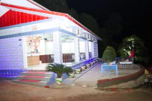 uma casa branca com um telhado vermelho e azul em Shalini Batika & Eco Resort em Tigri