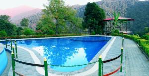 a swimming pool with a mountain in the background at Shalini Batika & Eco Resort in Tigri