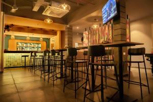 un bar con taburetes y TV en un restaurante en Sparrow Hotels managed by Siara, en Alwar