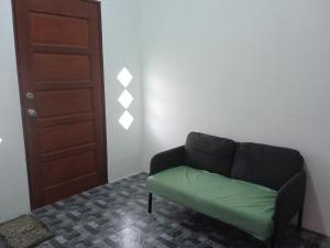 a living room with a green couch and a door at Homestay Idaman B B with 2 room aircond 2 Quen Bed and Not Sharing Room -Privacy in Kuala Terengganu