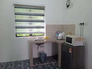 a small kitchen with a sink and a microwave at Homestay Idaman B B with 2 room aircond 2 Quen Bed and Not Sharing Room -Privacy in Kuala Terengganu