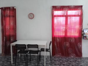 a table and chairs in a room with red curtains at Homestay Idaman B B with 2 room aircond 2 Quen Bed and Not Sharing Room -Privacy in Kuala Terengganu
