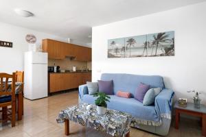 a living room with a blue couch and a kitchen at Apartamentos Bella Vista in Puerto del Carmen