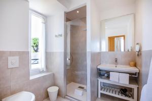 a white bathroom with a sink and a shower at Hotel La Bienvenue in La Croix-Valmer