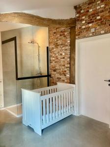 a white crib in a room with a brick wall at Hoeve De Kleinheide in Dessel