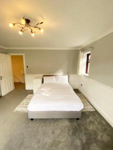 una camera con letto bianco e lampadario pendente di Emerson Park Mansion a Harold Wood