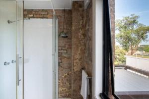 a glass shower in a bathroom with a brick wall at Stylish house - Moments to Kings Cross & The City in Sydney