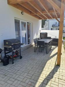 un patio con parrilla, mesa y sillas en Lipno Village Houses, en Frymburk