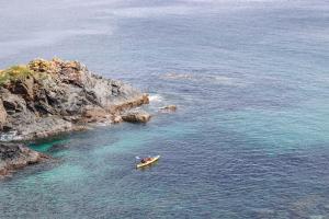 a yellow boat in the water next to a cliff at Housel Bay Hotel in Lizard