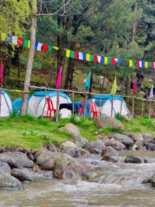 a group of tents next to a river with flags at RIVERFRONT CAMPS AND HIKES in Pahalgām