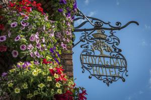 a sign hanging on the side of a building with flowers at The Royal Oak Hotel, Welshpool, Mid Wales in Welshpool