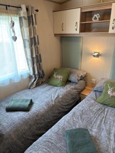 a small room with two beds and a window at Woodpecker lodge, Camelot Holiday Park, CA6 5SZ in Carlisle