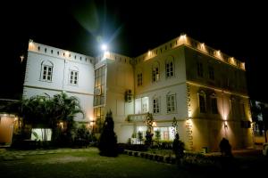 Un grand bâtiment blanc avec des lumières allumées la nuit dans l'établissement Hotel Maden Inn, à Itahari