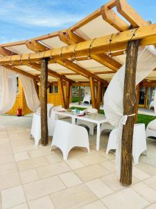 pérgola de madera con mesas blancas y sillas debajo en Complex Andris en Murighiol