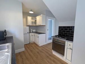 uma cozinha com armários brancos e um forno com placa de fogão em Alexander Apartments Benton Road em Newcastle upon Tyne