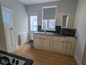 eine Küche mit einer Spüle und einer Mikrowelle in der Unterkunft Alexander Apartments Benton Road in Newcastle upon Tyne
