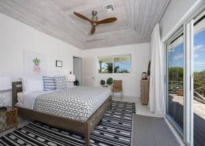 Schlafzimmer mit einem Bett und einem Deckenventilator in der Unterkunft Beachfront Bliss Private Estate with Cottages in Savannah Sound