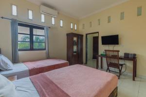 a bedroom with two beds and a desk and a television at Uma Sari Ubud Villas in Ubud