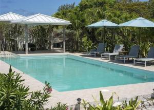 una piscina con sillas y sombrillas azules en Beachfront Bliss Private Estate with Cottages, en Savannah Sound
