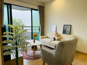 a living room with a couch and a chair and a plant at Mutiara Melaka Beach Resort by Minso in Tangga Batu