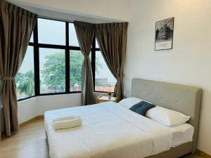 a bedroom with a white bed and large windows at Mutiara Melaka Beach Resort by Minso in Tangga Batu