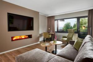 a living room with a couch and a fireplace at Sporthotel Grafenwald in Daun