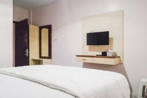 a white bedroom with a bed and a tv at RedDoorz at Pantai Panjang Bengkulu 2 Citandui in Bengkulu +15 photos