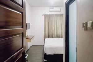 um pequeno quarto com uma cama e uma janela em RedDoorz at Pantai Panjang Bengkulu 2 em Bengkulu